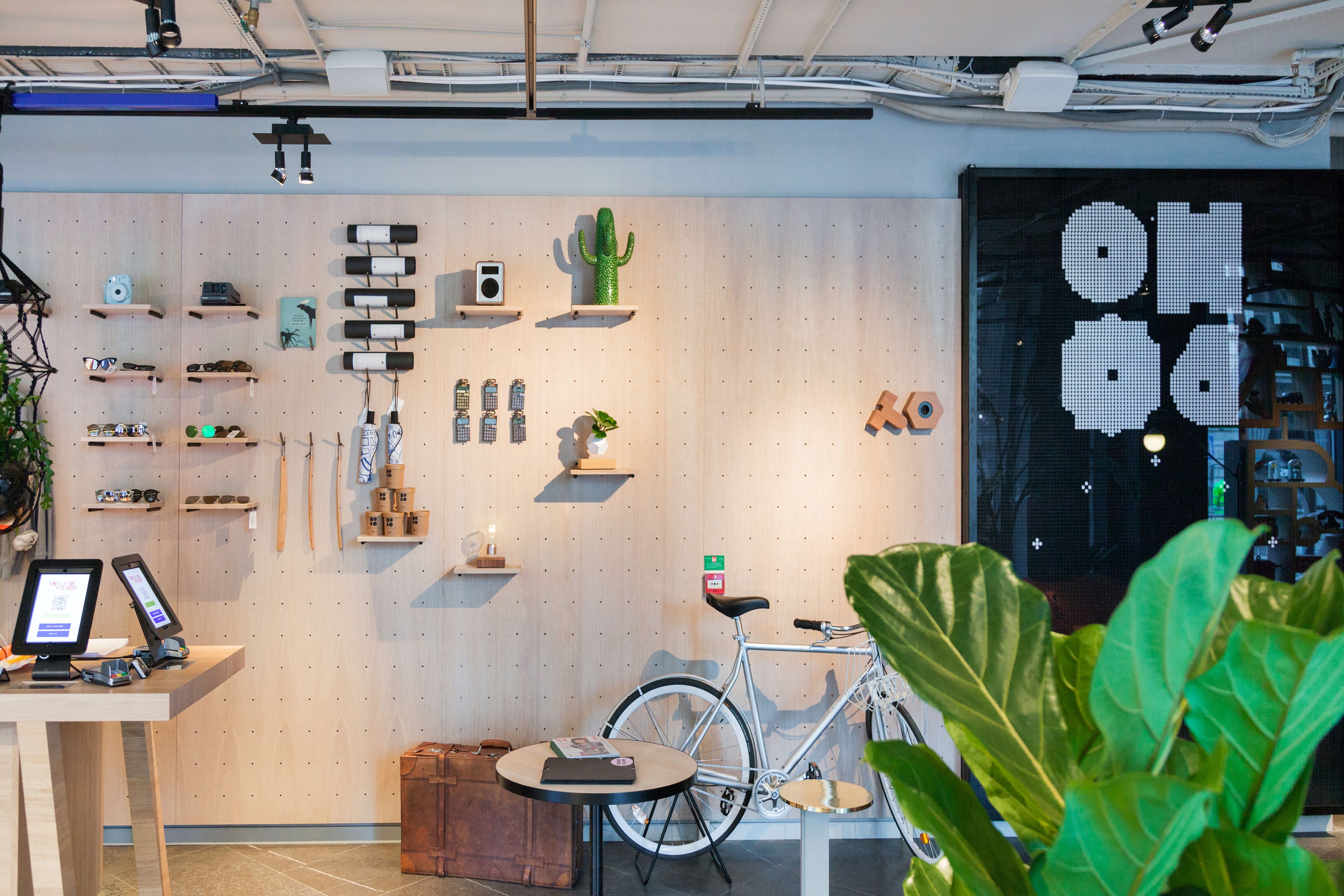 A modern interior with a bicycle, shelves with various items, and a digital display.