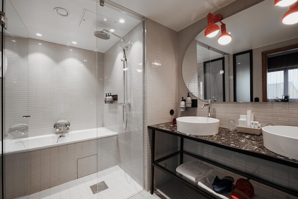 Une salle de bain moderne dotée d’une douche à parois de verre, d’un grand miroir et d’un comptoir en marbre.