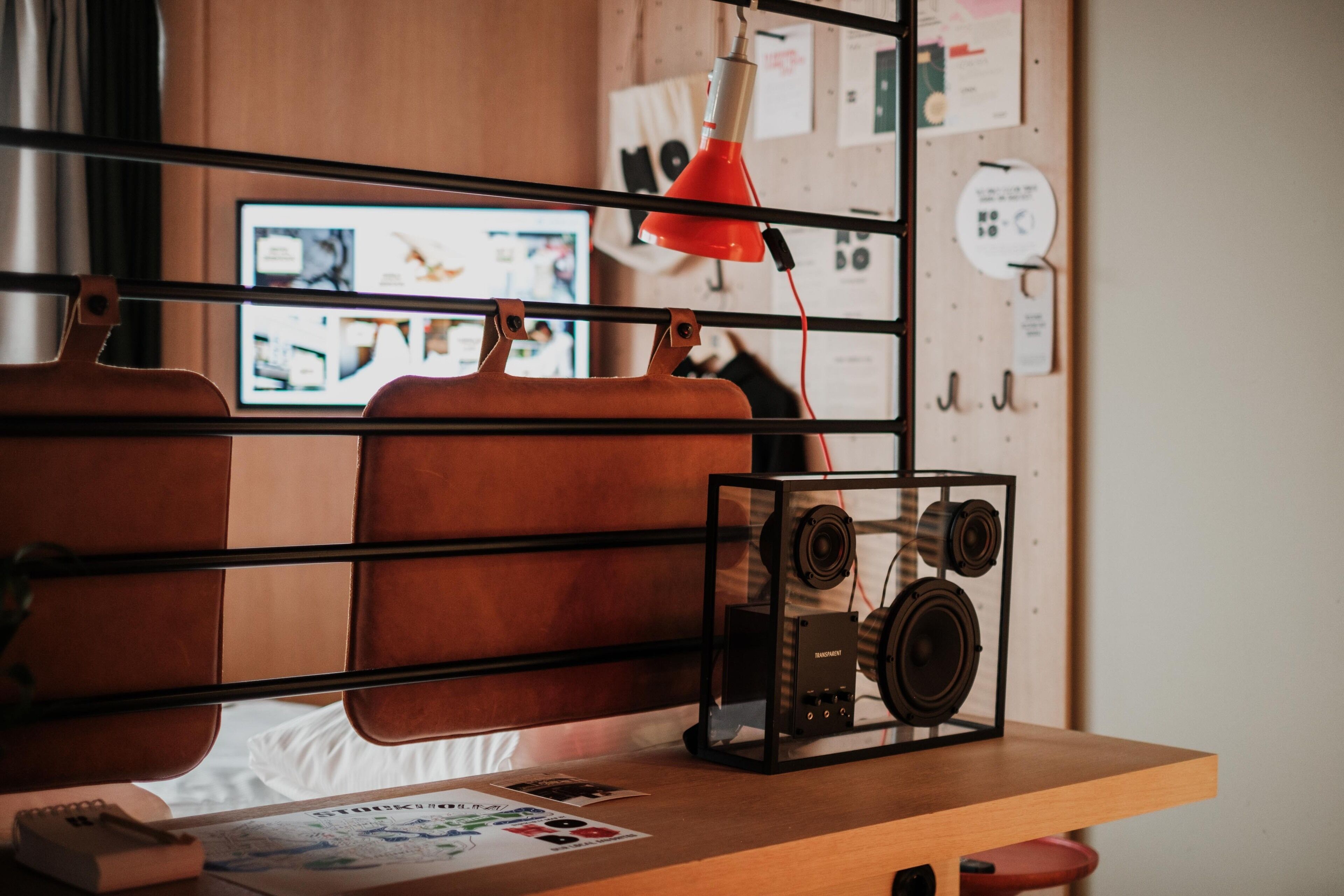 A wooden desk with a vintage radio, a red lamp, and a computer monitor in the background.