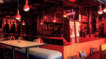 Un bar moderno con iluminación roja, cabinas y un letrero de neón.