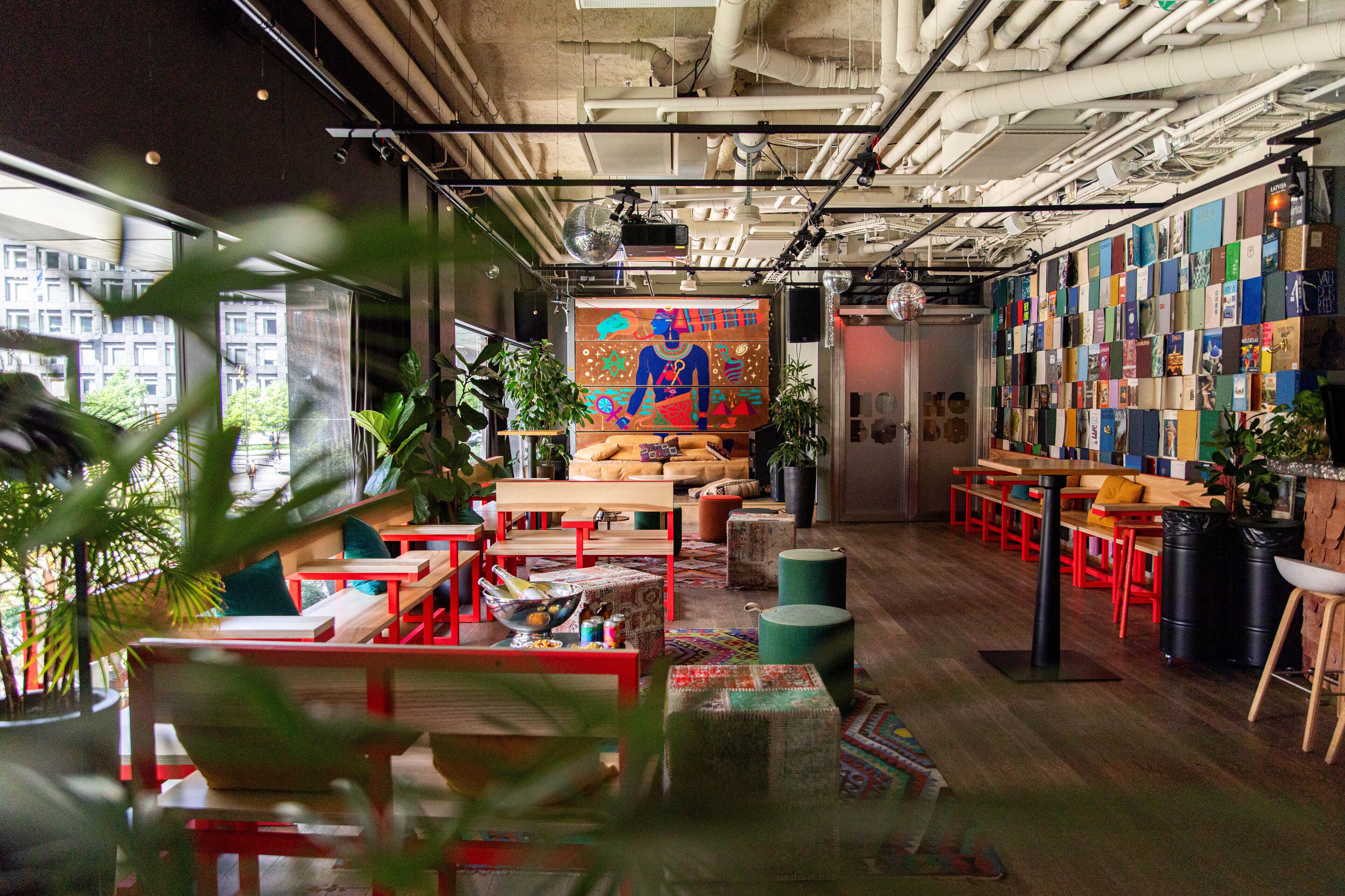 An interior with wooden tables, red chairs, and a colorful mural on the wall.