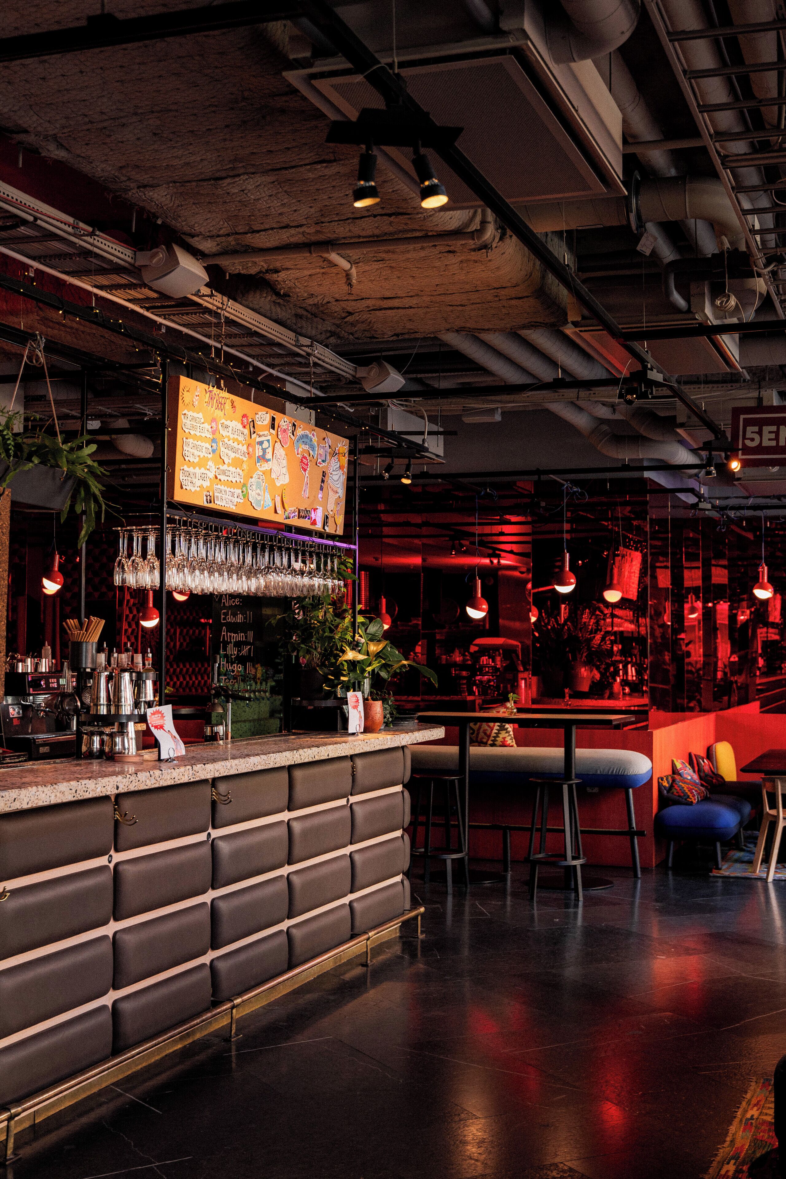 Una zona de bar con mostrador, taburetes y luces colgantes.
