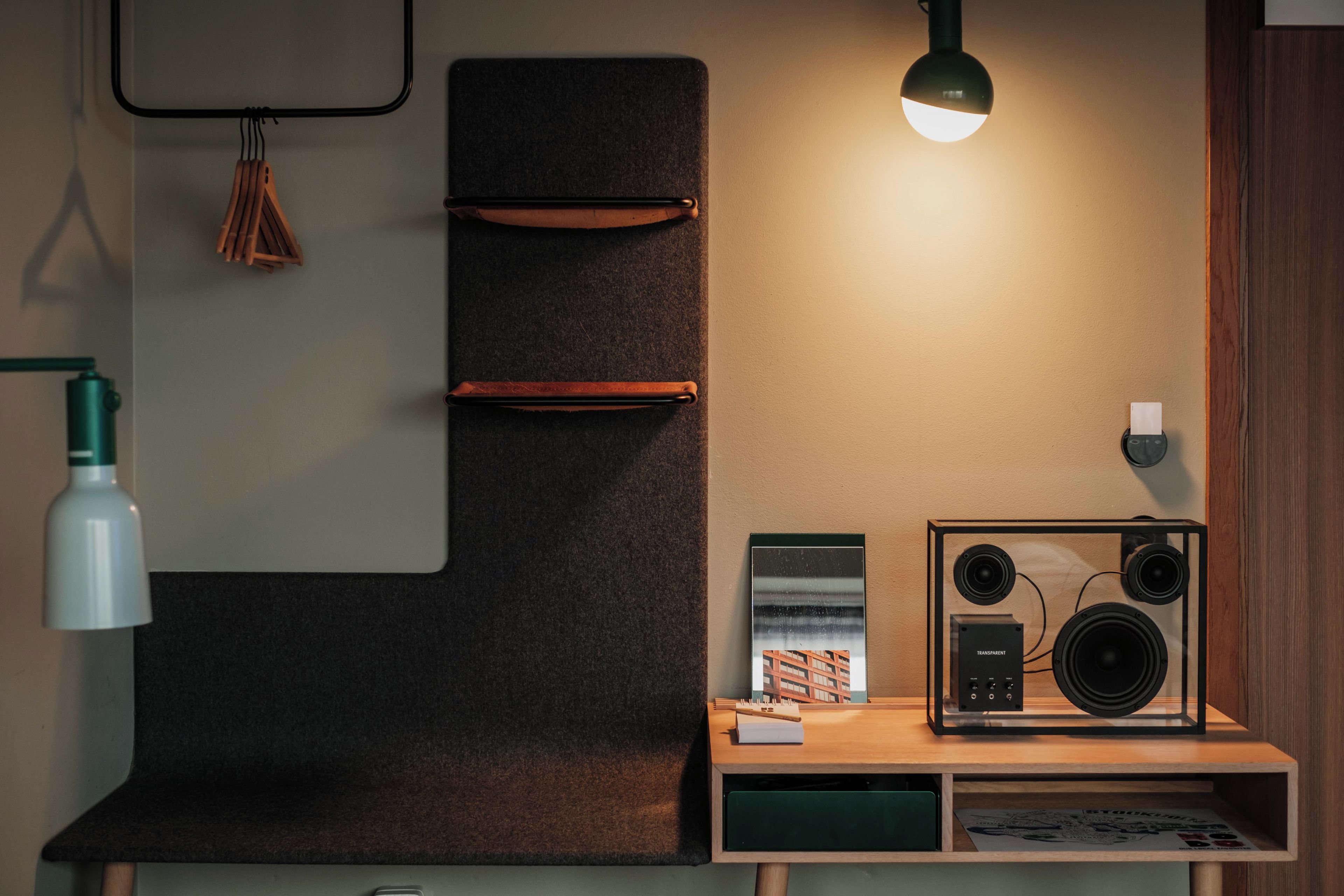 Ein modernes Zimmer mit einem Holzbüro, einer schwarzen Stereoanlage, einem gerahmten Bild und einer Pendelleuchte.