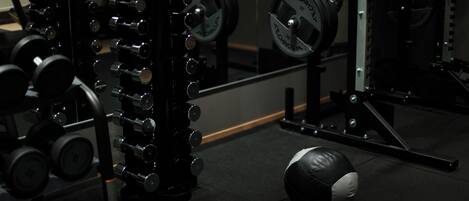 A gym with weightlifting equipment, including dumbbells and barbells.