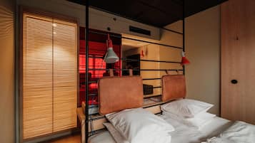 A bunk bed with a wooden headboard, a window with blinds, and two pendant lights.