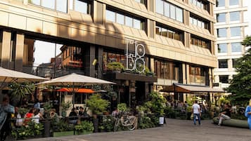 Een modern gebouw met een cafégedeelte, buiten zitplaatsen en plantenpotten.