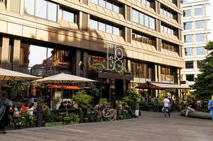 A modern building with a cafe area featuring outdoor seating and potted plants.