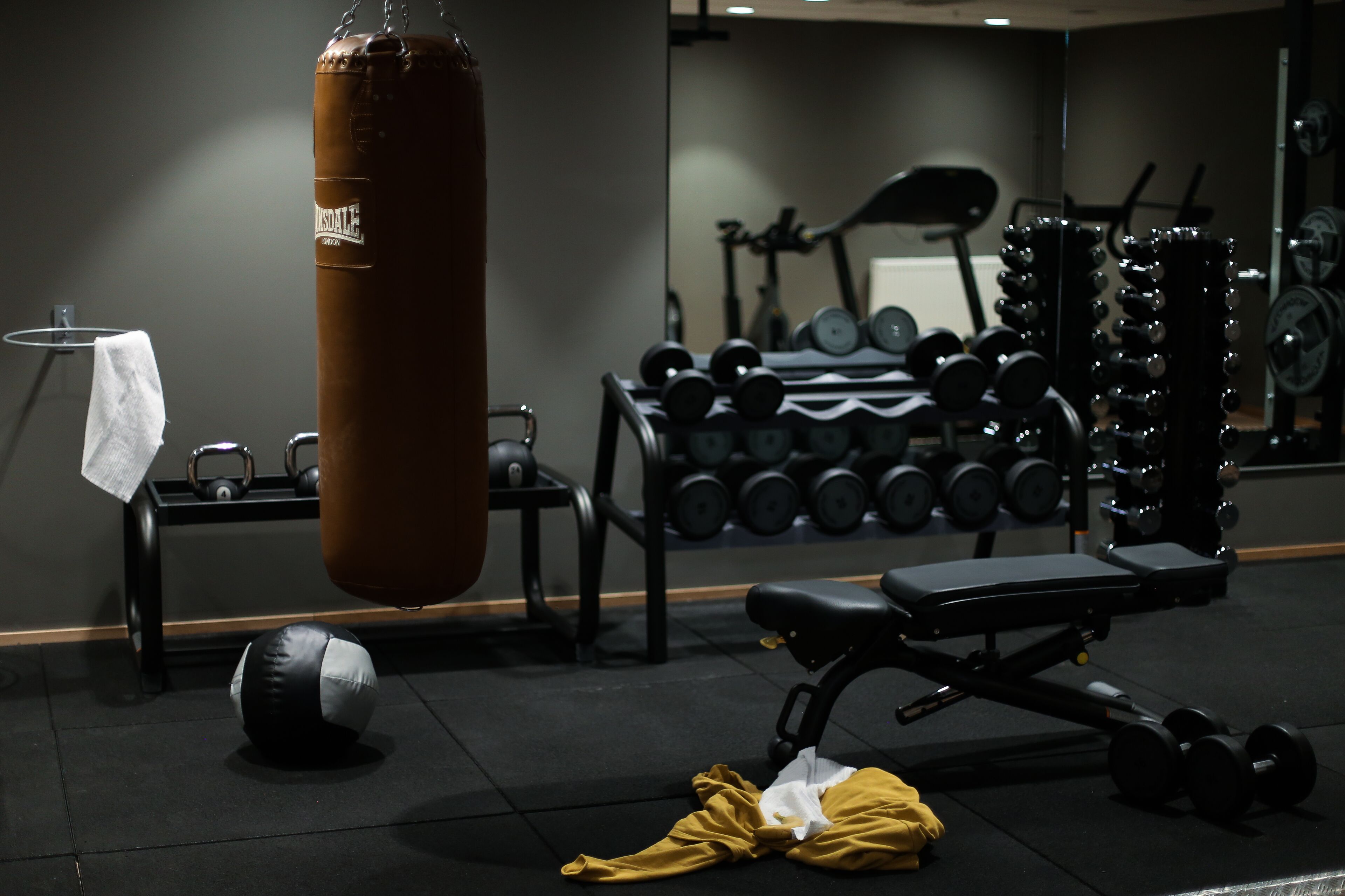 Ett gym med en boxningssäck, hantlar och en träningsbänk.
