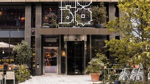 Un edificio con entrada moderna, plantas en macetas y bicicletas estacionadas afuera.