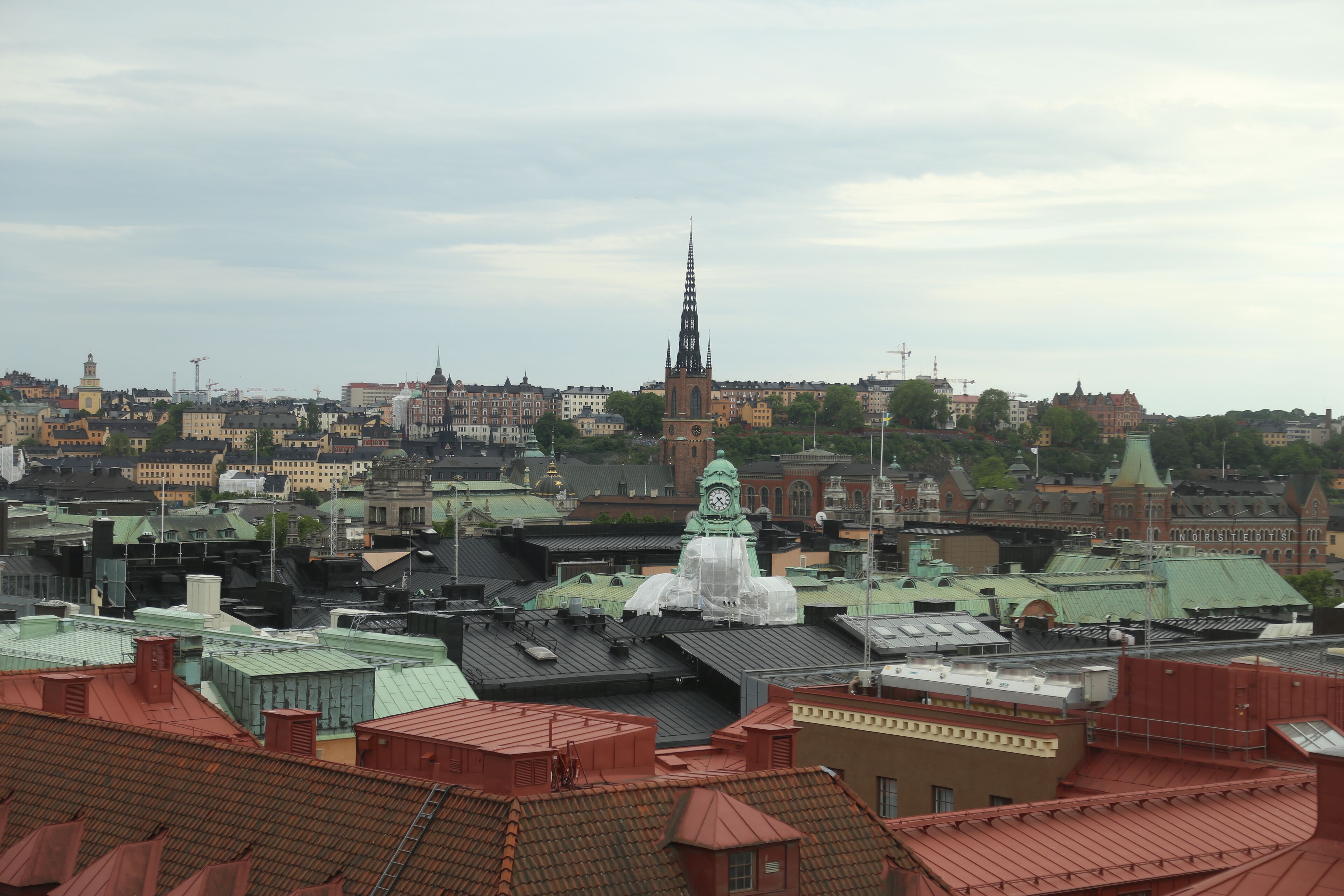 Een stadsgezicht met een opvallende kerktoren, diverse gebouwen en daken.