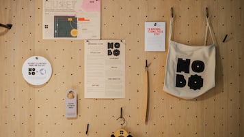 A wooden pegboard wall with various items including a map, a menu, a sign, a bag, and a hanger with a black garment.
