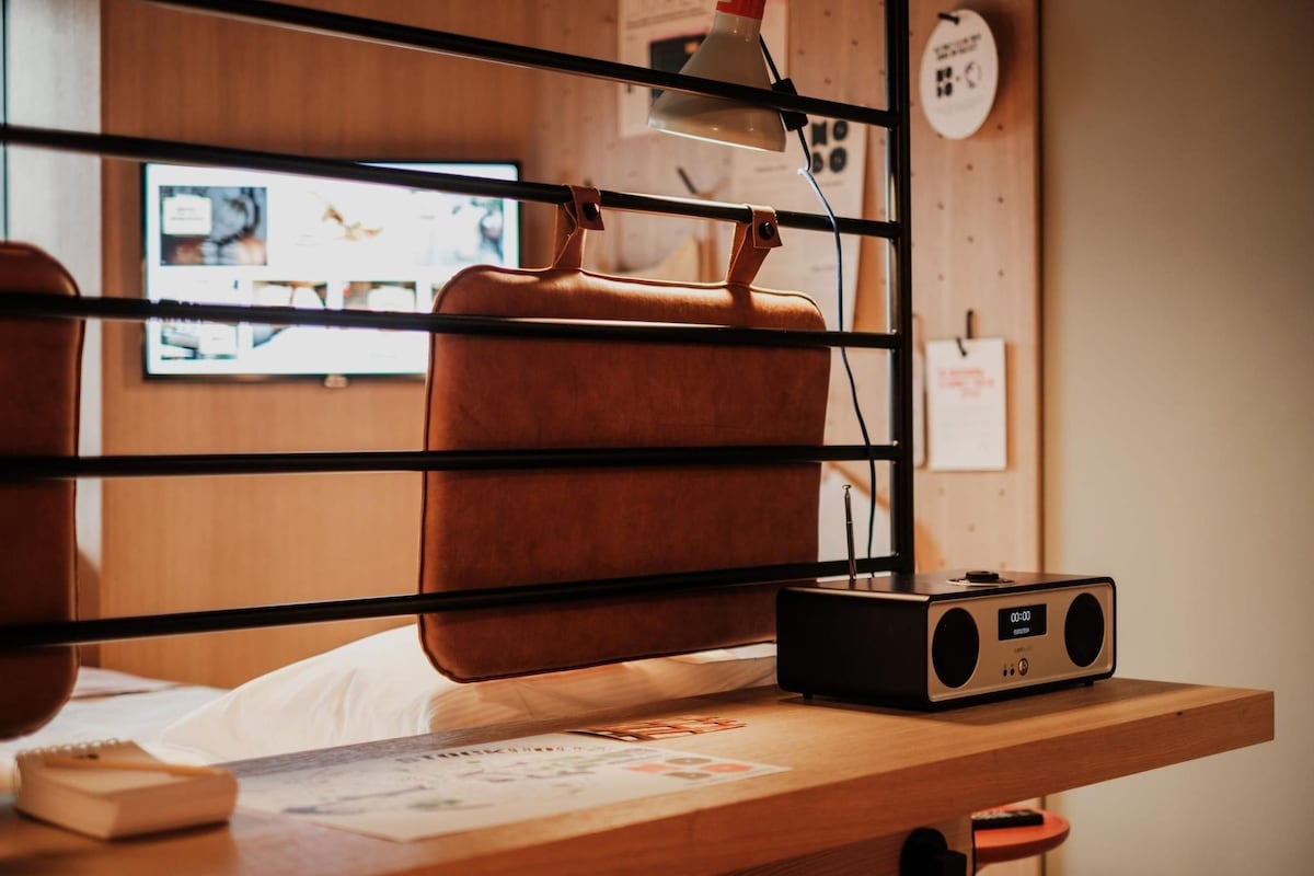 A wooden desk with a radio, a lamp, and a chair.