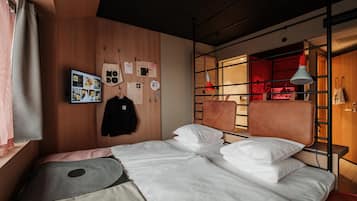 A modern bedroom with a wooden wall, a bed with white bedding, a hanging light, and a red accent wall.