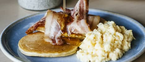 A breakfast plate with pancakes, bacon, and cottage cheese.