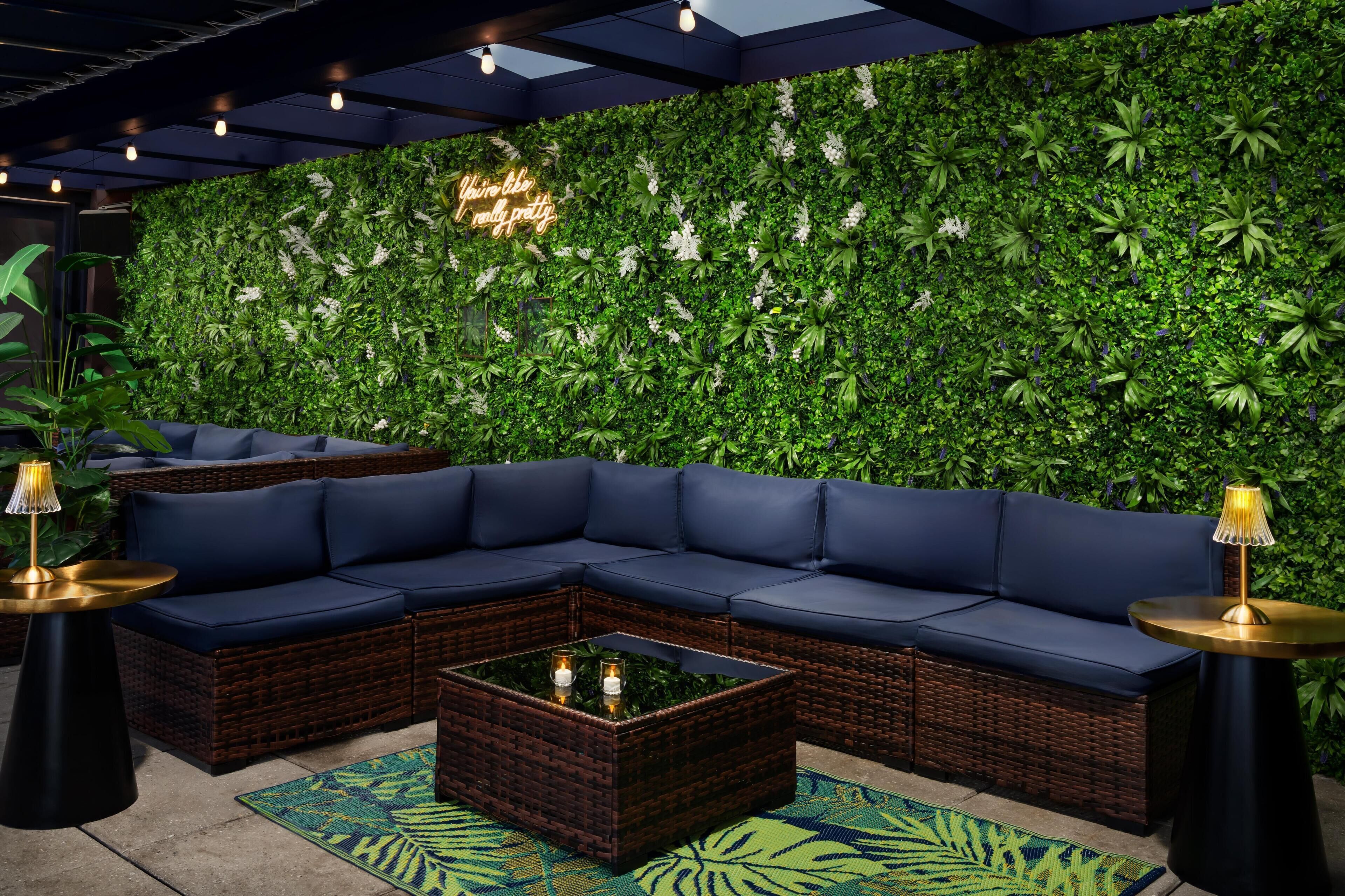 A modern lounge area with a green wall, blue sofa, and two side tables with lamps.