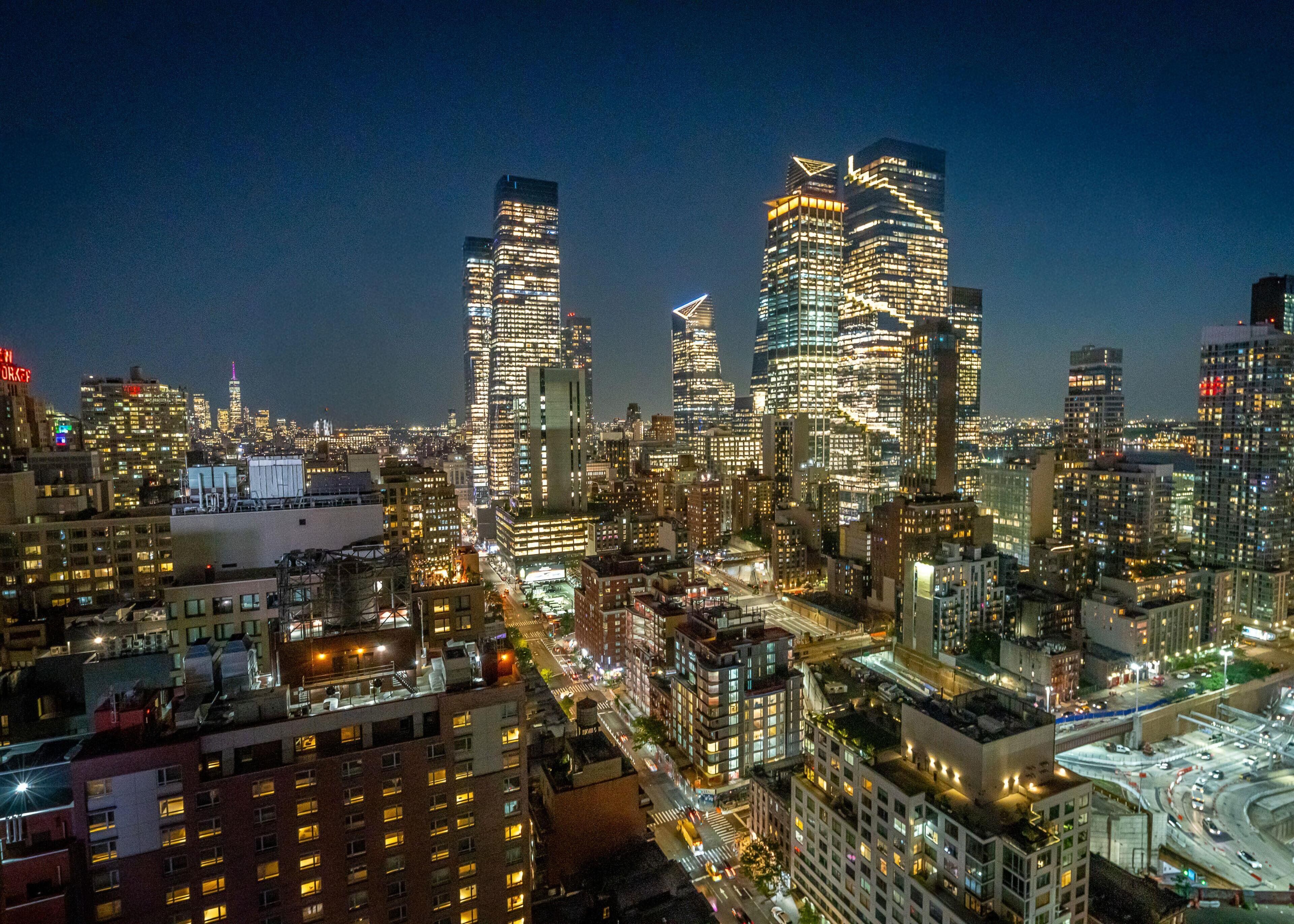A cityscape at night with illuminated skyscrapers and a busy highway.