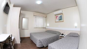 A hotel room with two beds, a desk, a chair, a TV, a window with curtains, and a picture on the wall.
