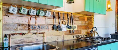 A kitchen with teal cabinets, a stainless steel sink, and a stove.