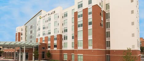 A multi-story hotel with a modern design, featuring a mix of brick and glass facades, and a covered entrance area.