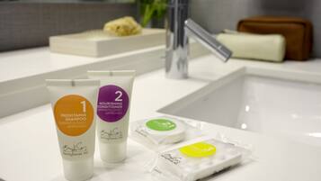 A bathroom with a white sink, two bottles of skincare products, a bar of soap, and a toothbrush.