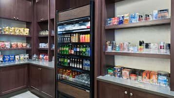 Una tienda de comestibles con estantes llenos de botanas, bebidas y artículos para el hogar.