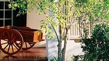 A wooden cart on a porch with a window and plants in the background.
