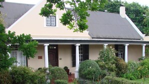 A two-story house with a beige facade, white columns, and a dark roof. - Die Waenhuis Guest House (George)