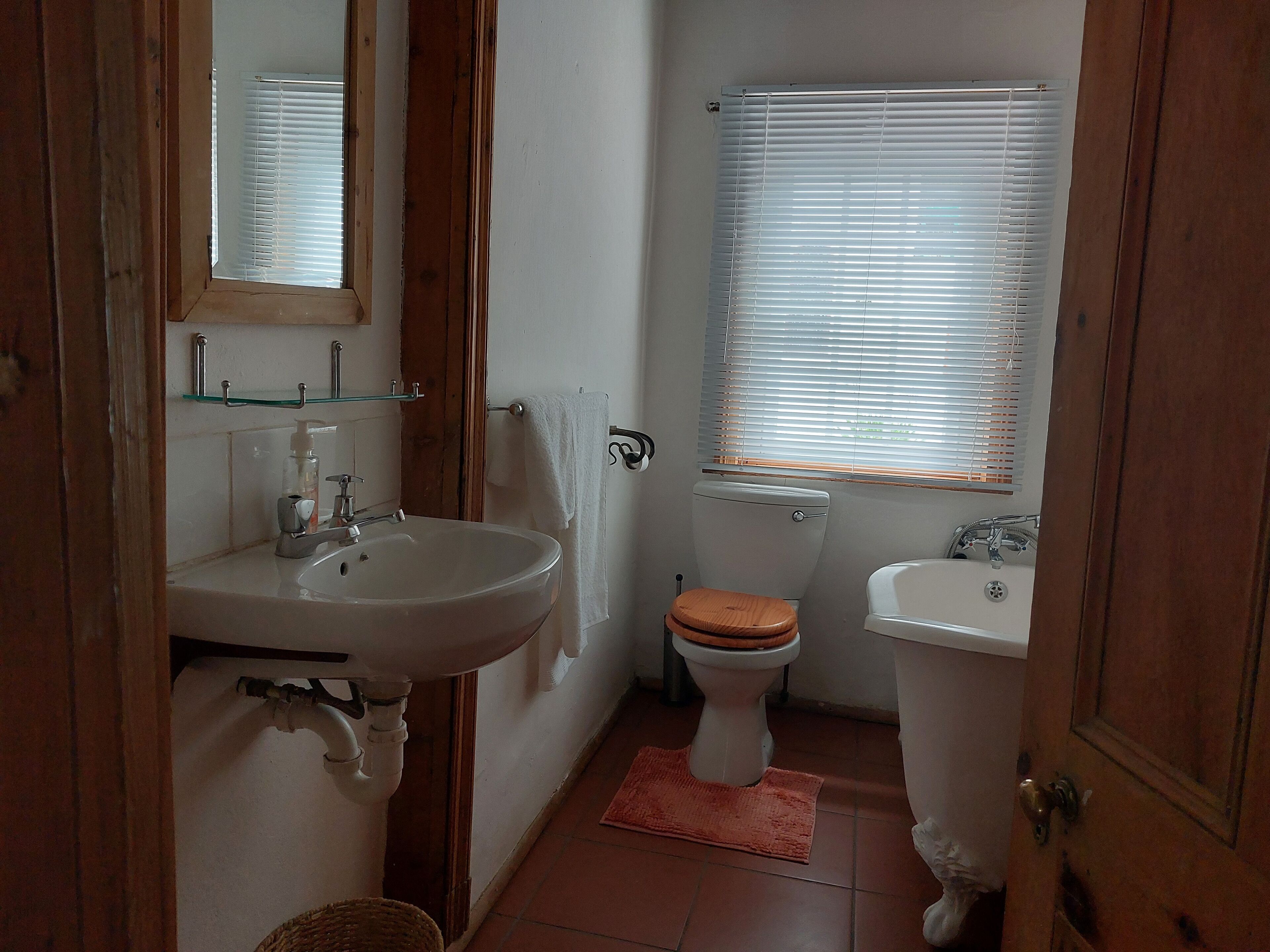 Ein Badezimmer mit Waschbecken, Toilette und Fenster mit Jalousien.