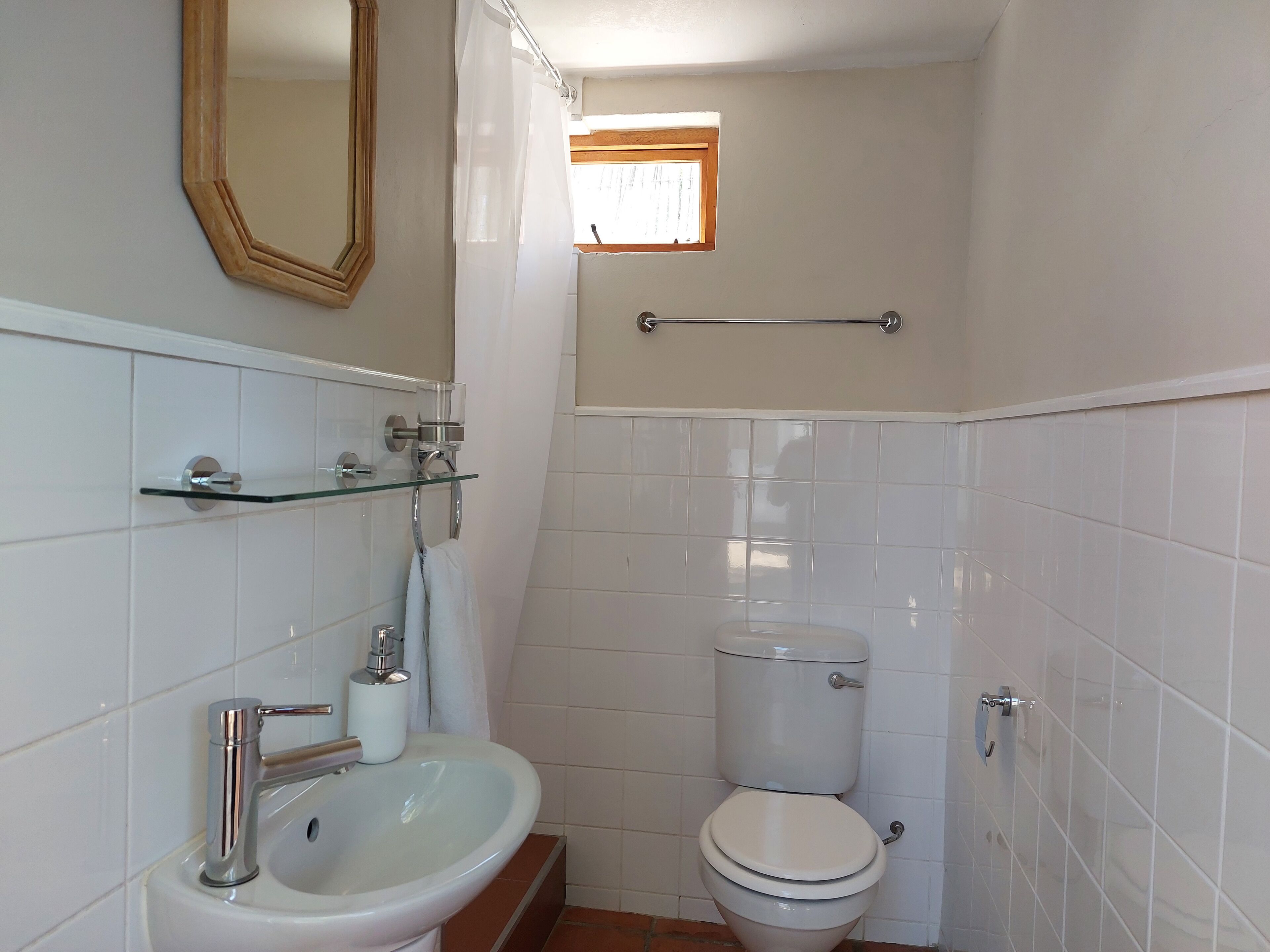 A small bathroom with a toilet, sink, and mirror.
