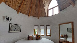 A spacious bedroom with a large bed, a wooden ceiling, and a large mirror.
