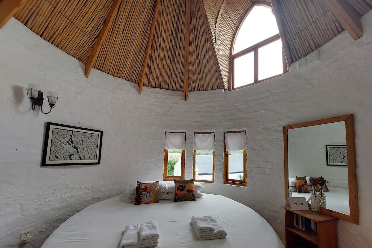 Een ruime slaapkamer met een groot bed, een houten plafond en een grote spiegel.