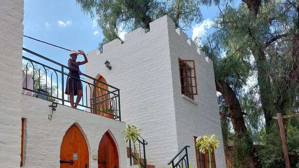 A white building with arched doorways and a balcony with a metal railing.