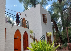 Um edifício branco com portas em arco e uma varanda com guarda-corpo de metal.