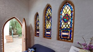 A room with a blue sofa, three stained glass windows, and a welcome sign.