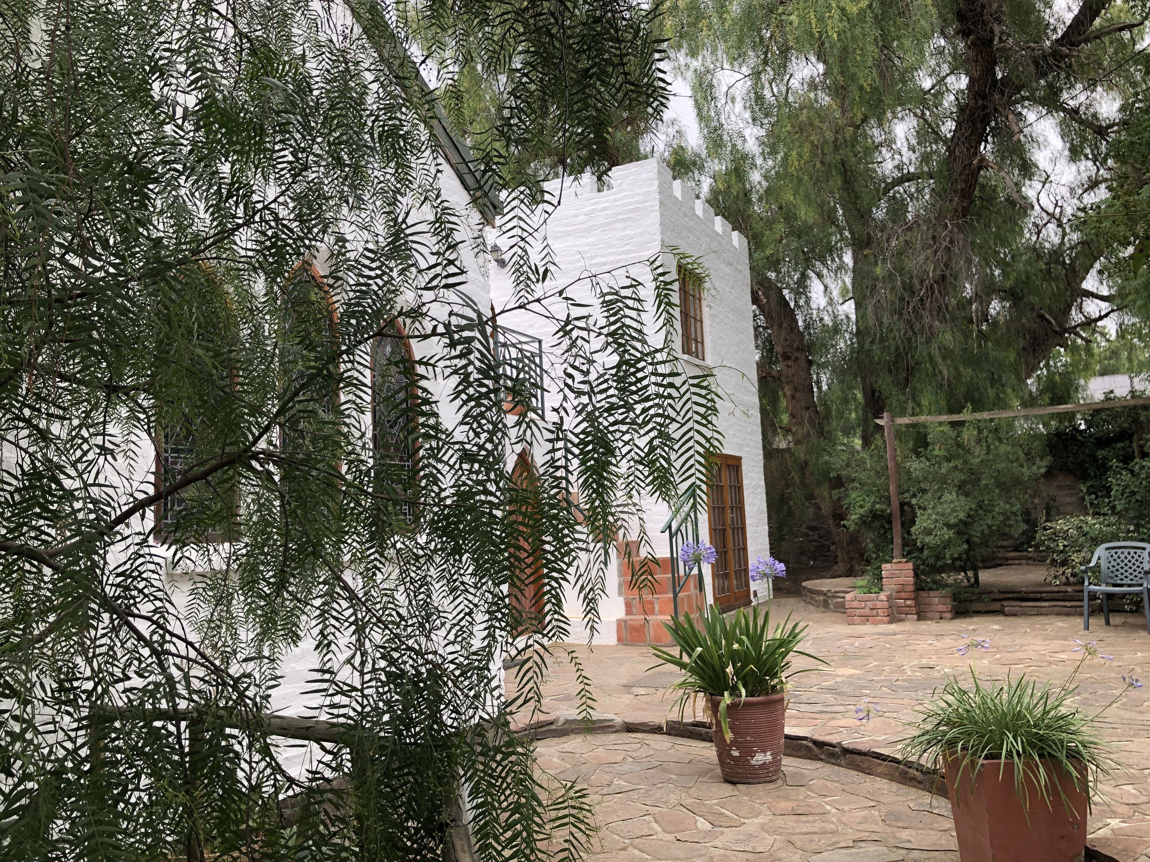 A courtyard with a white building, potted plants, and a stone pathway.