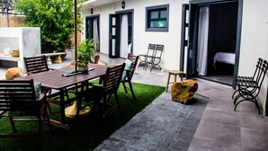 Un patio con una mesa y sillas de madera, una sombrilla verde y una jardinera de piedra.