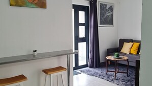 Una sala moderna con un sofá, una mesita y una zona de bar con taburetes.