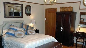 A bedroom with a bed, bedside lamps, a wardrobe, and a desk with a chair.