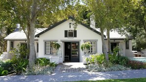 A two-story house with a central entrance, surrounded by lush greenery and a well-maintained lawn. - Rose Cottage (Franschhoek)