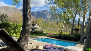 A poolside area with lounge chairs, a hat, and a blanket. - Rose Cottage (Franschhoek)