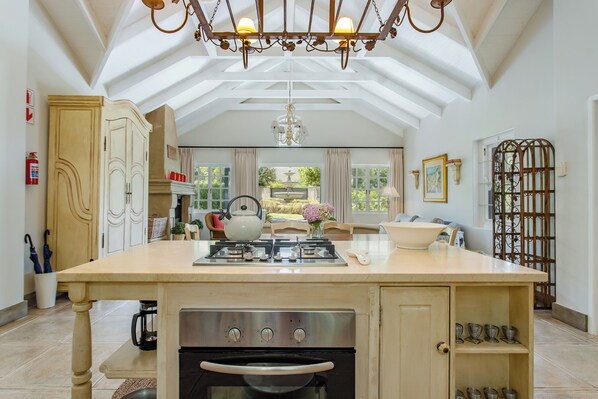 A spacious kitchen with a central island, a gas stove, an oven, and a chandelier.