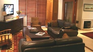 Una sala de estar con un sofá, sillones, una mesa de centro, un televisor y una chimenea.