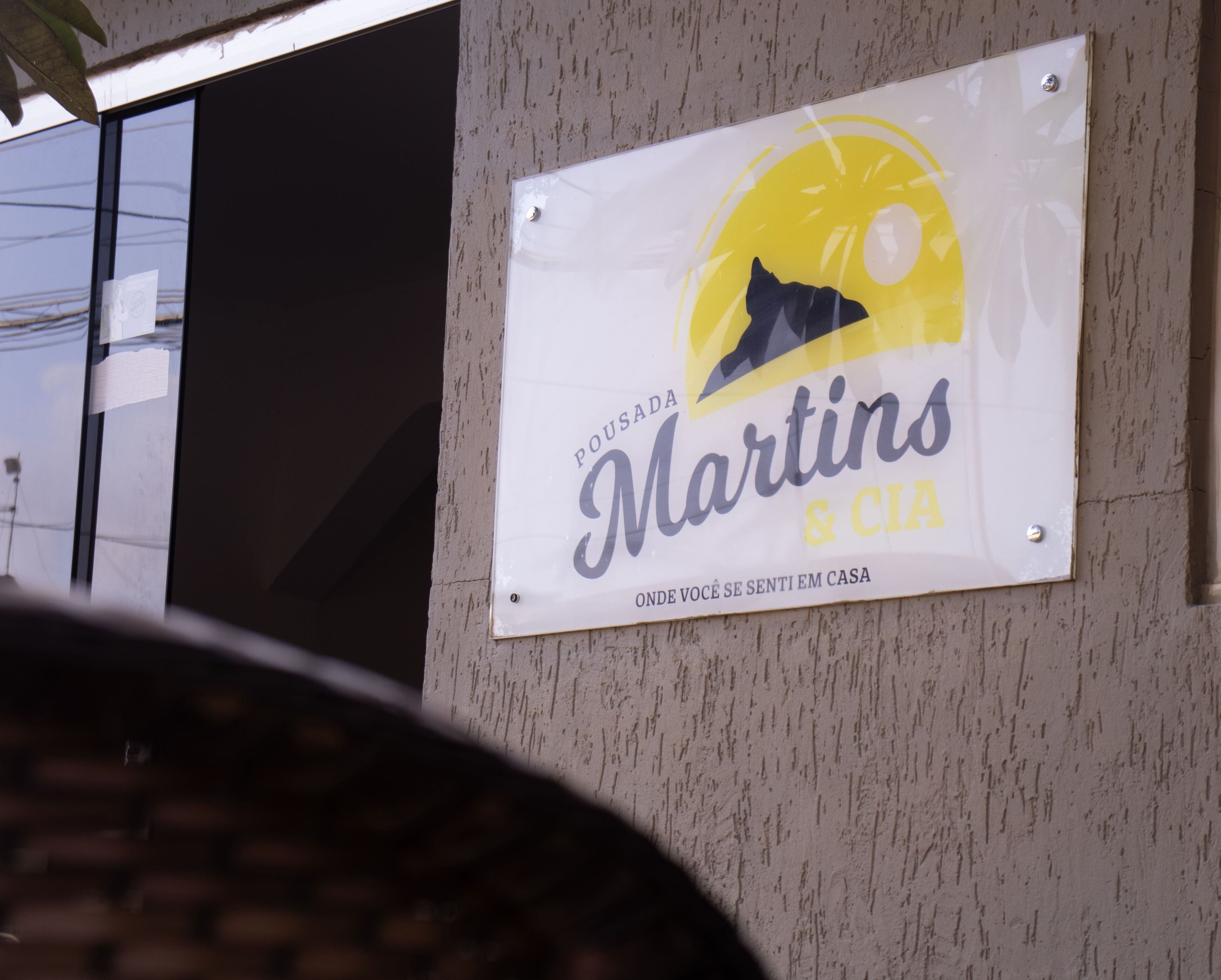 Letrero de 'Pousada Martins & CIA' con un sol y silueta de montañas.