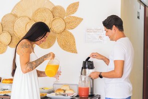 Una habitación con una decoración grande tejida en la pared, una mesa con alimentos y una cafetera.