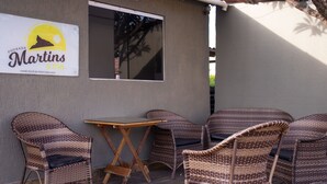 Un espace patio aménagé avec des meubles en osier, une table en bois et un panneau indiquant « Pousada Martins & CIA ».