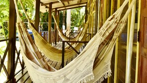 A hammock under a wooden structure with a view of greenery outside. - Pousada Boldro Home (Fernando de Noronha)