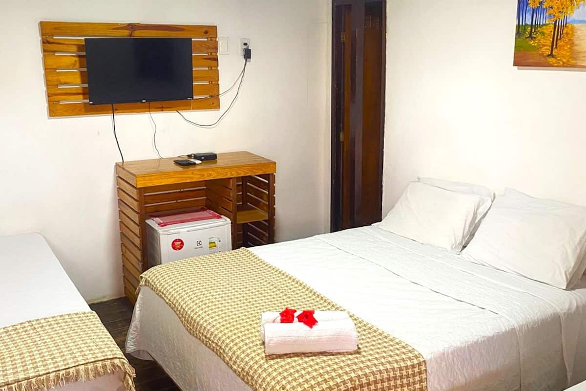 A hotel room with two beds, a TV mounted on the wall, a wooden nightstand, and a painting.