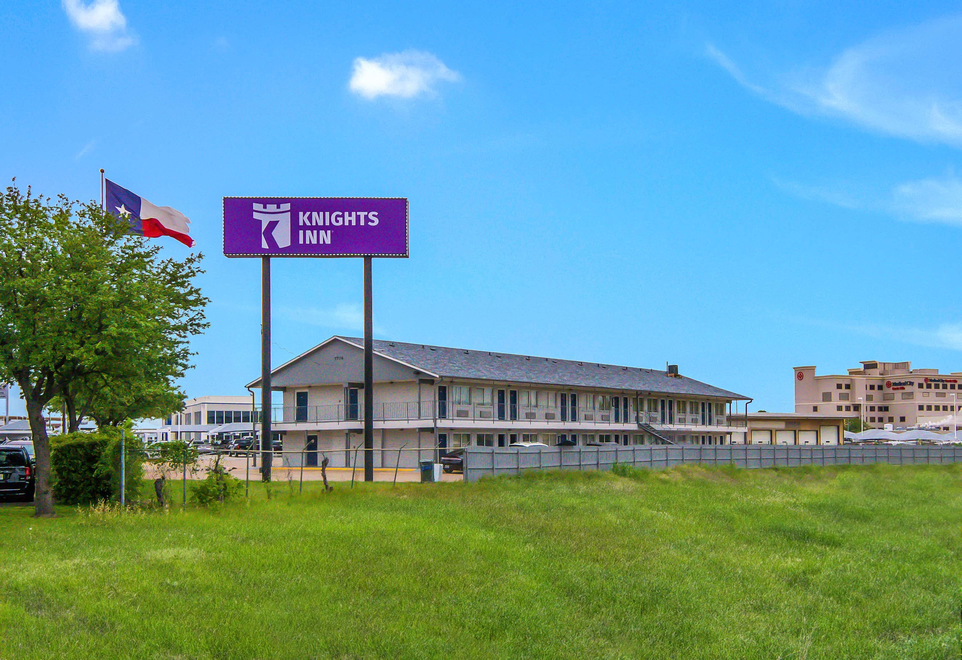 A motel with a sign for the Knights Inn, featuring a two-story building with a flat roof and a parking lot in front.