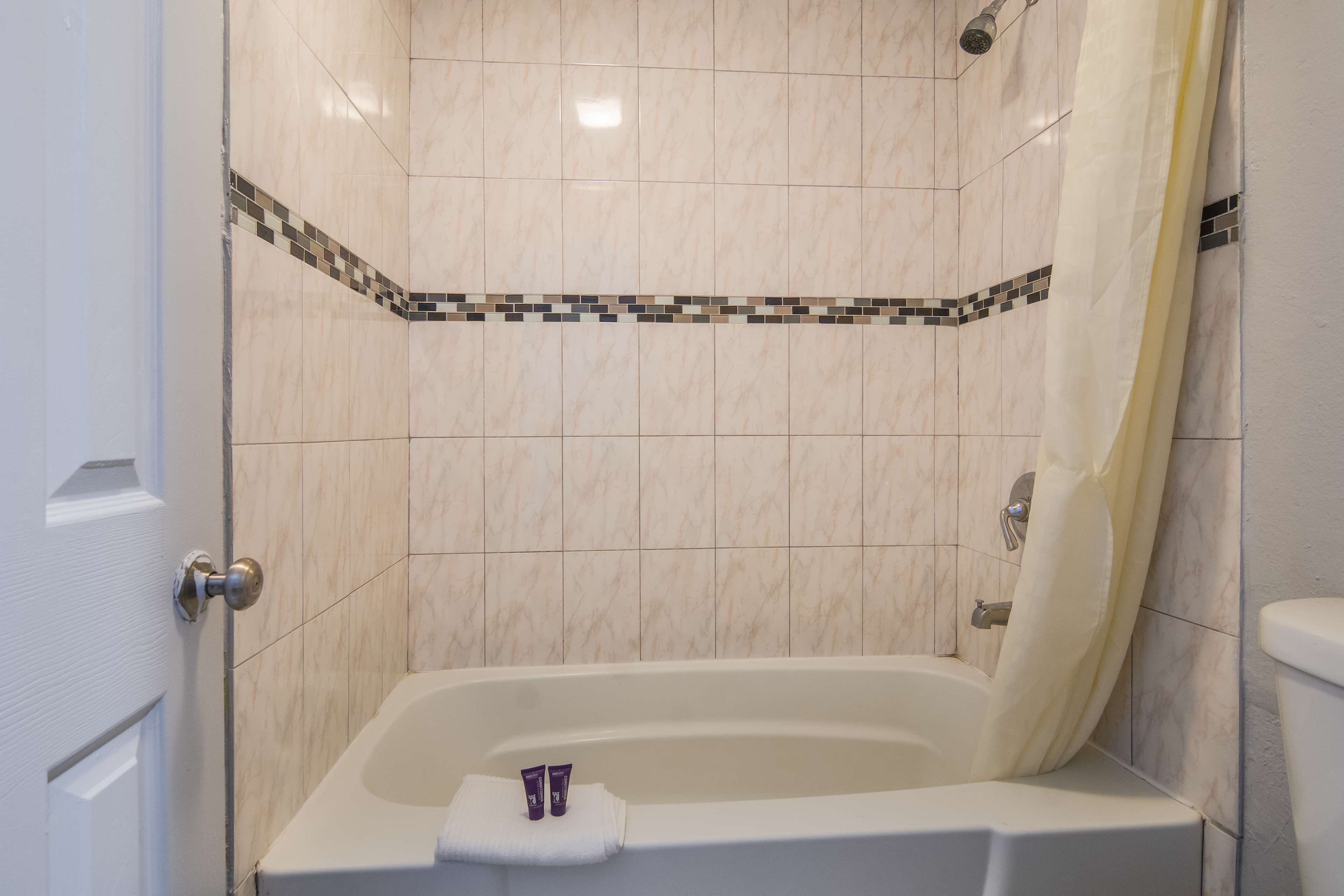 A bathroom with a bathtub, a shower curtain, and a toilet.