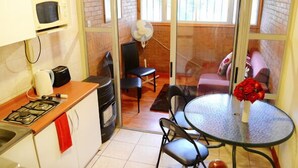 Una cocina compacta con estufa a gas, microondas y un pequeño comedor con mesa y sillas.